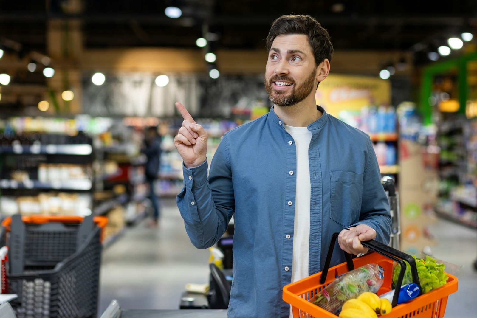 Man shopping for groceries pointing upwards