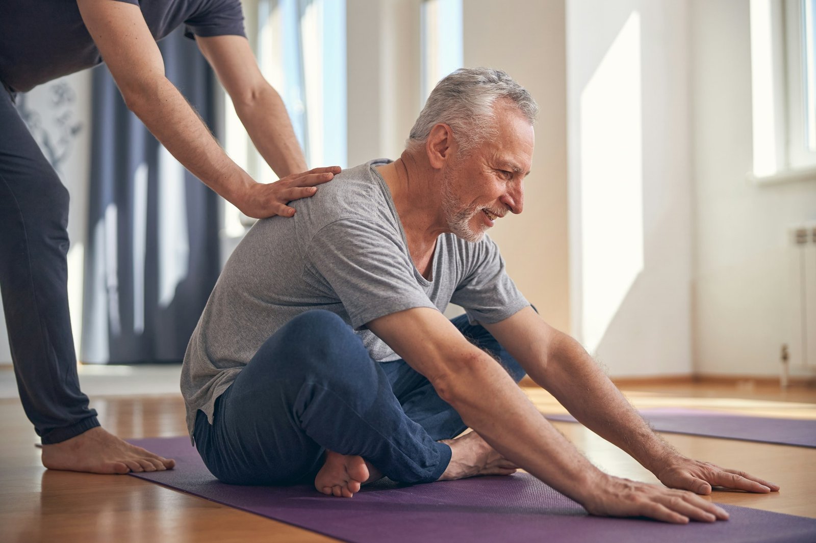 Smiling male performing a basic seated yoga exercise
