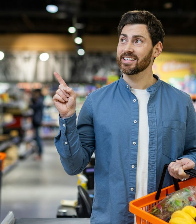 Man shopping for groceries pointing upwards Man shopping for groceries pointing upwards