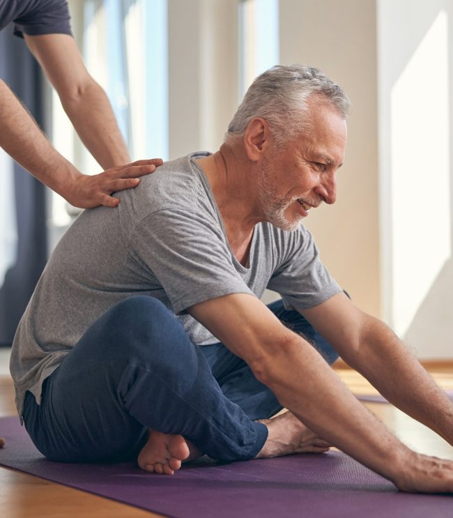 Smiling male performing a basic seated yoga exercise Smiling male performing a basic seated yoga exercise
